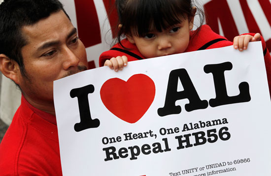 A man and daughter hold an "I heart AL" sign in protest of Alabama's HB 56 law.